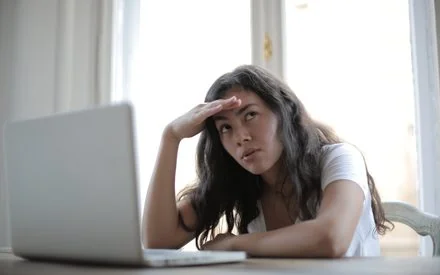 Woman at her laptop looking distracted